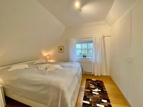 biała sypialnia z łóżkiem i oknem w obiekcie Eichenhof (Vollerwiek) w mieście Grothusenkoog