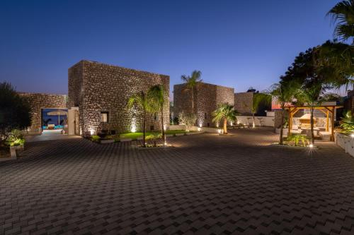 a building with a courtyard with palm trees at night at Lido White Villa in Pefki Rhodes