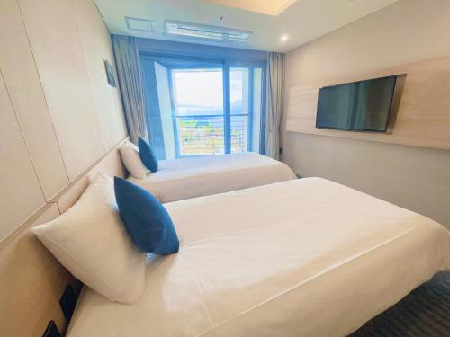a hotel room with two beds and a television at Hotel bridge Seogwipo in Seogwipo
