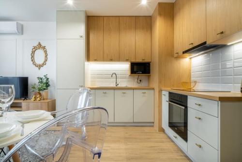 a kitchen with white cabinets and a table and chairs at ApartamentySnu, Struga Tower Double Gold z parkingiem in Radom
