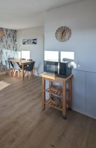 Il comprend une cuisine équipée d'un four micro-ondes et d'une table avec des chaises. dans l'établissement Nina studio 5 Places avec vue sur la baie au pied des commerces Classé 3 étoiles, à Pornichet
