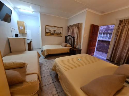 a small hotel room with two beds and a couch at Motel Villa Africa in Polokwane