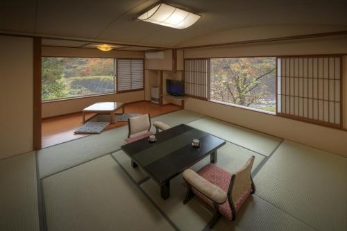 um quarto com uma mesa, cadeiras e janelas em Harumiya Ryokan em Fukushima