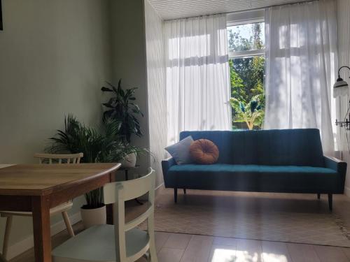 a living room with a blue couch and a window at Appartement 'de Stadstuin' in Harderwijk