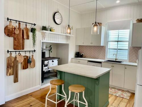 a kitchen with a green island and two stools at Gorgeous Arthouse Queenslander In Ipswich in Bundamba