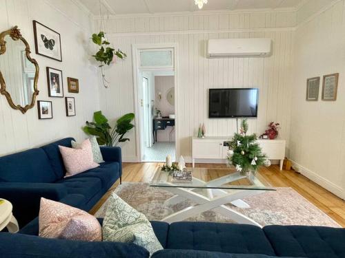 a living room with a blue couch and a glass table at Gorgeous Arthouse Queenslander In Ipswich in Bundamba