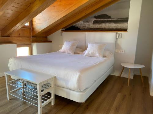 1 dormitorio con cama blanca y mesa en Apartamentos Mundaka Surf Camp, en Mundaka
