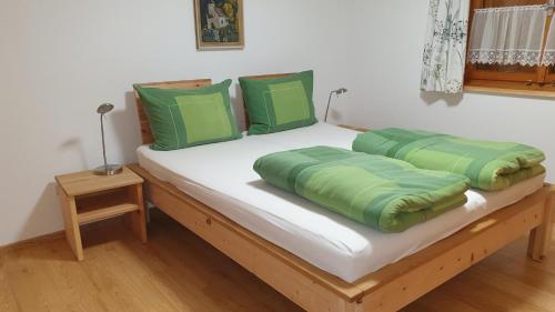 a bed with green pillows on top of it at Apartment Sonnenbüchel in Wald am Arlberg