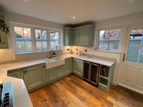 uma cozinha com armários verdes e pisos e janelas em madeira em Central Knutsford em Knutsford