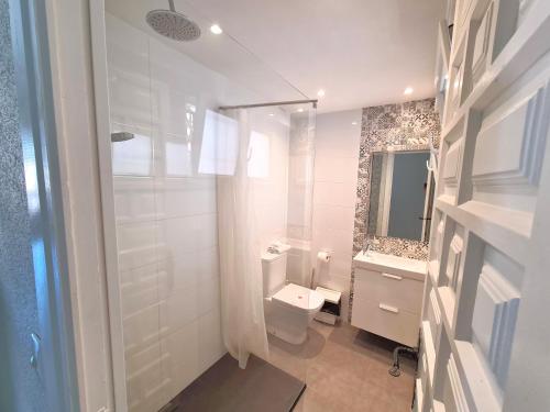 La salle de bains est pourvue de toilettes, d'un lavabo et d'un miroir. dans l'établissement Apartamentos Strand Jávea, à Jávea