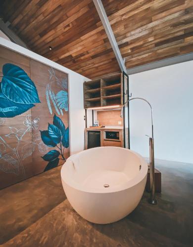 a large bath tub in a room with a painting at Island Escape Burasari in Phuket Town