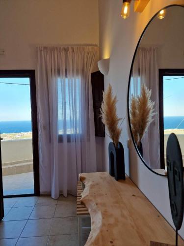 a room with a mirror and a table with a view of the ocean at Amerisa Suites & Villa in Fira