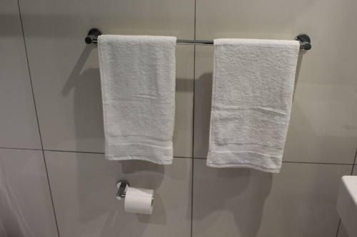 two white towels hanging on a shower door in a bathroom at Favour's 2 Bedroom Apartment on 77 in Windhoek