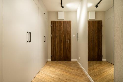 a hallway with two wooden doors in a room at ApartamentySnu, Struga Tower Gold z parkingiem in Radom