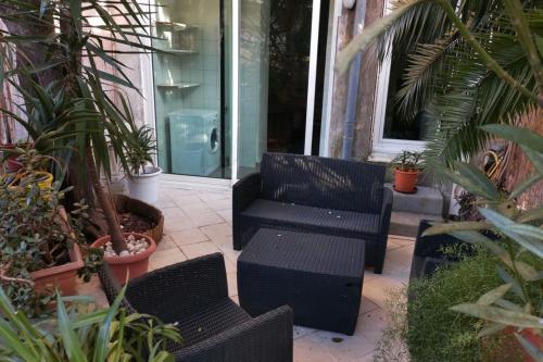 un patio avec une chaise noire, des tables et des plantes dans l'établissement Large studio 37 m with terrace, à Nice