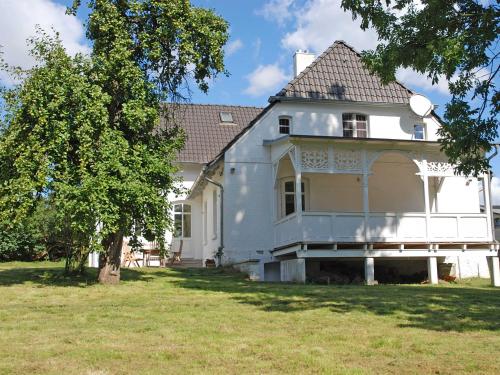 une grande maison blanche avec un arbre dans la cour dans l'établissement Gutshaus Glowitz, à Glowitz