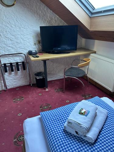 a room with a desk and a bed and a table with a television at Hotel Söllner in Tettau