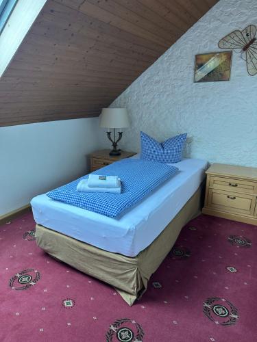 a bedroom with a bed with blue sheets and blue pillows at Hotel Söllner in Tettau