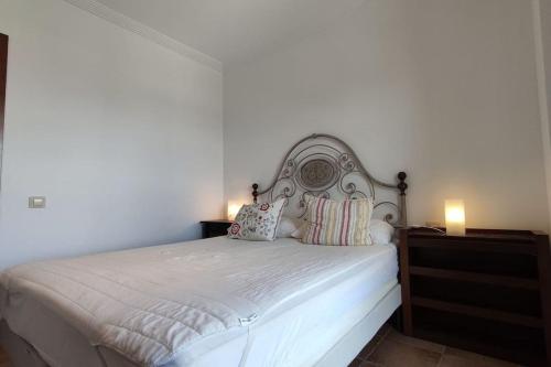 a bedroom with a white bed with two pillows at Apartamento Los Pelícanos in Isla Canela