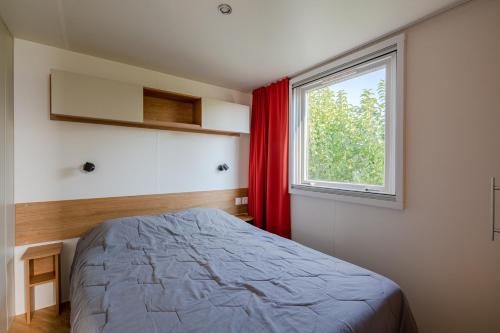 um quarto com uma cama e uma janela em Mobil home Cécile em Fréjus