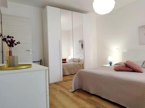 a white bedroom with a bed and a mirror at Casa Phimes in Calatafimi