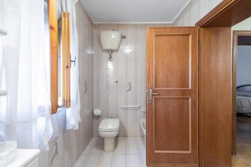 a bathroom with a toilet and a wooden door at Le Balze nel cuore della Toscana in Castelfranco Piandisco