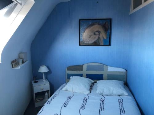une chambre bleue avec un lit et un tableau mural dans l'établissement L'appartement entre ciel et mer, à La Turballe