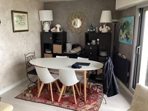 une salle à manger avec une table et des chaises blanches dans l'établissement L'appartement entre ciel et mer, à La Turballe