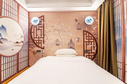 Puzzle Hotel - Zhongshan 8th Road Chenjiaci Subway Station Branch في قوانغتشو: غرفة نوم بسرير وجدار به لوحات