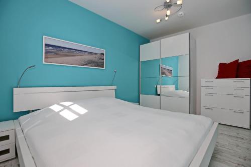 um quarto com uma cama branca e paredes azuis em Residenz von Flotow Wohnung 13 em Heiligendamm
