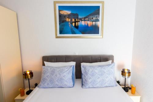 a bed with two pillows and a picture above it at Apartment Rose Pool Comfort in Dubrovnik