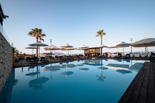 a swimming pool with chairs and umbrellas at Alas Resort & Spa in Elia Laconias