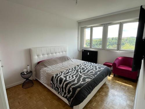 - une chambre avec un lit noir et blanc et une chaise rouge dans l'établissement Appartement EPINAL calme, à Épinal