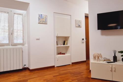 a white living room with a tv and a book shelf at My House&Apartments in Agrate Brianza