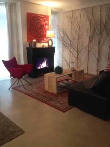 a living room with a fireplace and a red chair at L’atelier de Graslin in Nantes