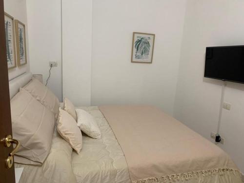 1 cama con sábanas blancas y almohadas en una habitación en APPARTAMENTO CAMPO IMPERATORE, en Castel del Monte