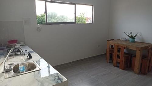 eine Küche mit einem Waschbecken, einem Tisch und einem Fenster in der Unterkunft Apartamento Cómodo y encantador en cartagena in Cartagena de Indias