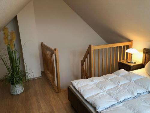 a bedroom with a bed with white sheets and a plant at Strandstr_ in Zingst