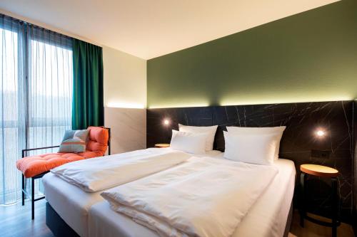 una camera d'albergo con un grande letto e una sedia di ACHAT Hotel Stuttgart Airport Messe a Stoccarda