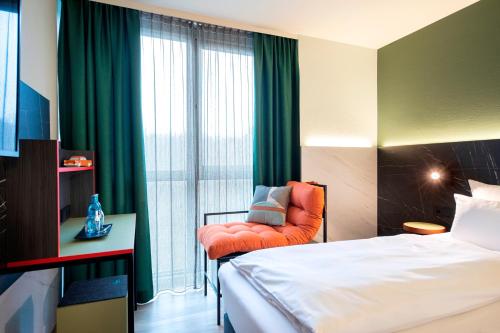 a hotel room with a bed and a chair and a window at ACHAT Hotel Stuttgart Airport Messe in Stuttgart