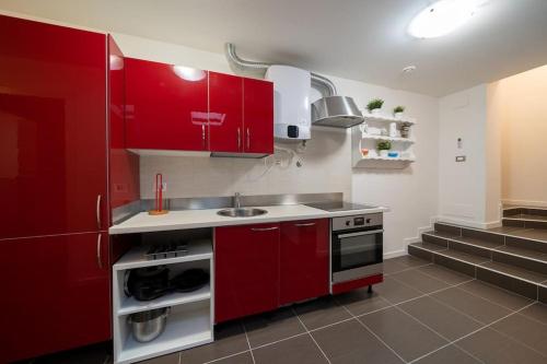 una cucina con armadi rossi e lavandino di Beat House&Apartments: ABBA a Cernusco sul Naviglio