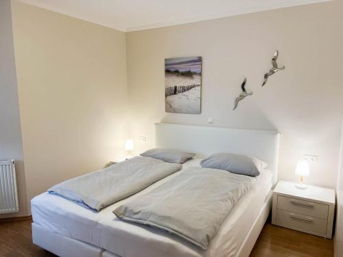 a bedroom with a large white bed with two lamps at Haus Ankerplatz Apartment 2 2 in Büsum