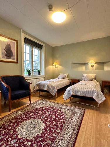 a bedroom with two beds and a chair and a rug at Forvalterboligen in Hadsund