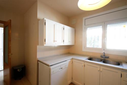 a kitchen with white cabinets and a sink and a window at Villa Dorada in Montroig