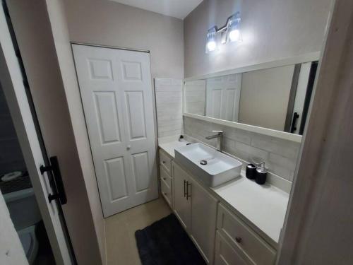 a white bathroom with a sink and a mirror at Suite at the Courtleigh Towers in Kingston