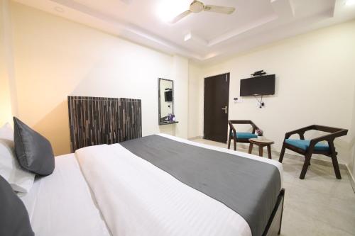 a bedroom with a bed and a tv and chairs at Perfectstayz Value Umra Grace - Near Haridwar Railway Station in Haridwār