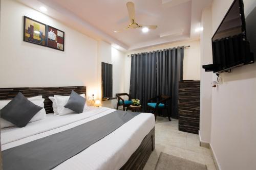 a bedroom with a bed and a flat screen tv at Umra Grace - Hotel in Haridwar By Perfect Stayz in Haridwār