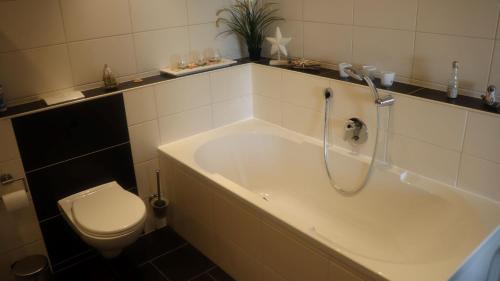 a bathroom with a bath tub and a toilet at Ferienwohnung Deichblick in Dornumersiel