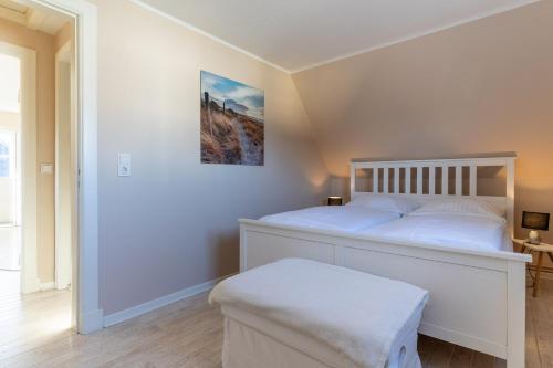 ein Schlafzimmer mit einem weißen Bett und einem Bild an der Wand in der Unterkunft Kleinod Appartement Stina in Sankt Peter-Ording