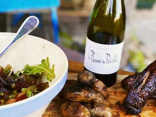 a bottle of wine next to a bowl of food and a bowl of mushrooms at La Calade in Montouliers